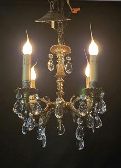 an antique chandelier with crystal drops hanging from it's arms and two candles in the middle