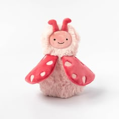 a pink and white stuffed animal with polka dots on it's wings, sitting against a white background