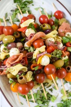 a white plate topped with lots of different types of food on skewered sticks