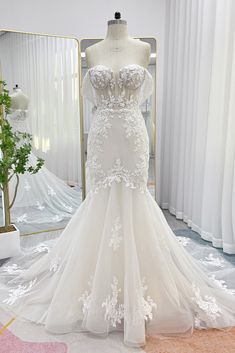 a white wedding dress on display in front of a mirror and mannequins