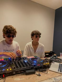 two people sitting at a table with dj equipment