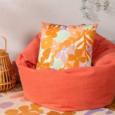 an orange bean bag chair sitting on top of a rug next to a lamp and lantern