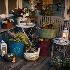 several potted plants are sitting on the front porch with tea kettles and lanterns