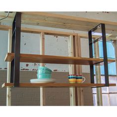 a shelf with cups and mugs on it in the middle of a room under construction