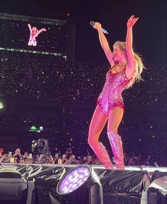 the woman is performing on stage with her arms in the air