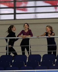 three girls are laughing while standing on the bleachers