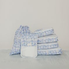 a stack of blue and white folded sheets on top of each other next to a drawstring bag