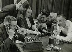 a group of people sitting around a table with an old phone in front of them