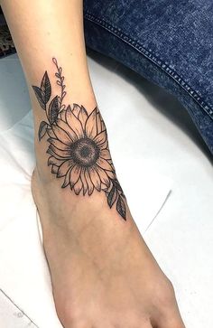 a woman's foot with a sunflower tattoo on it