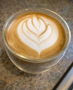 there is a cup of coffee that has been made in the shape of a leaf