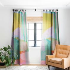 a chair sitting in front of a window next to a potted plant and rug