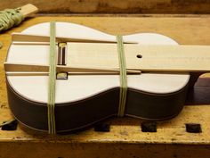 a wooden guitar is sitting on a table with some string tied around it's neck