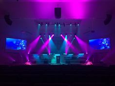 an empty auditorium filled with purple and blue lights, as the stage is set up for a concert