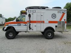 an ambulance is parked in the gravel near some trees