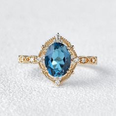 an oval blue topaz ring with diamond accents on the sides, set in yellow gold and white gold