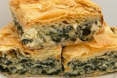 three pieces of spinach and cheese pastry stacked on top of each other in a white plate