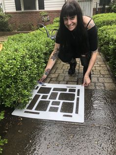 a woman kneeling down next to a cut out of a keyboard on top of a sidewalk