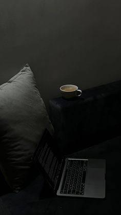 an open laptop computer sitting on top of a bed next to a cup of coffee