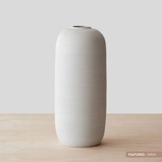 a white vase sitting on top of a wooden table