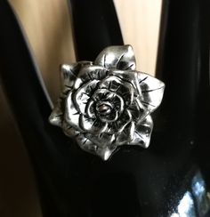 a silver ring sitting on top of a black plastic object in the shape of a flower