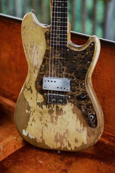 an old guitar sitting on top of a wooden bench