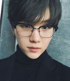 a young man wearing glasses and a black turtle neck sweater