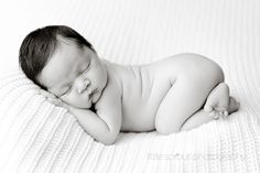 a baby laying on top of a bed with it's hands under his chin