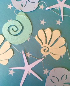 paper cut out of sea shells and starfishs on a blue background with white stars