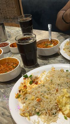 a table topped with plates of food next to bowls of soup and drinks on top of a table