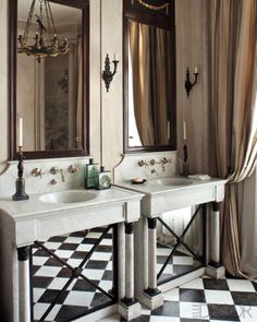 a bathroom with two sinks, mirrors and chandelier in the middle of it