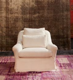 a white chair sitting on top of a purple rug next to a brown and red wall