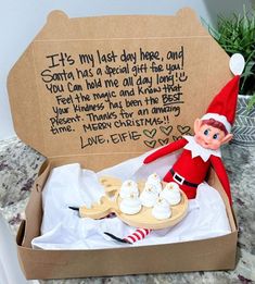 an elf is sitting in a box with some cupcakes and marshmallows