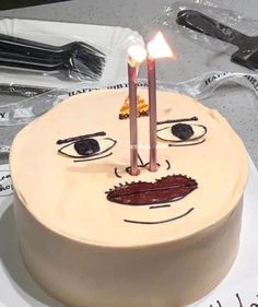 a birthday cake with two candles sticking out of it's face, and the candle is lit