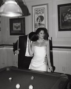 a man and woman standing next to a pool table