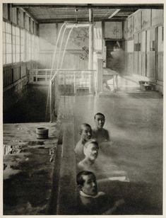 black and white photograph of three men in an industrial building with water coming from the ceiling