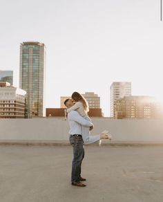 a man holding a woman in his arms while standing on top of a building roof