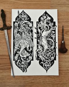 two black and white designs on paper next to scissors