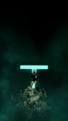 a woman standing on top of a pile of people in the dark with green light