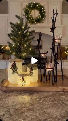 a christmas tree in a jar on a tray with candles and wreaths around it