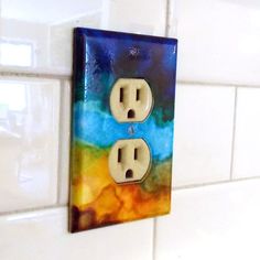 a colorful light switch cover on a white tile wall