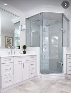 a white bathroom with a walk in shower next to a sink and mirror on the wall