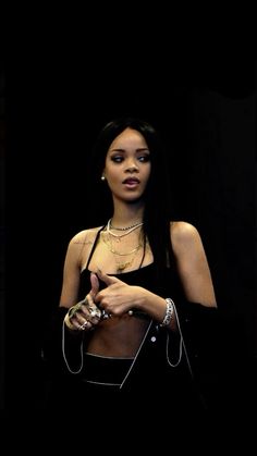 a woman in a black dress holding a handbag and looking at the camera with an intense look on her face