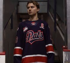 a young man standing in front of a wall wearing a hockey jersey with the word pats on it