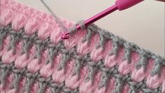 the crochet stitch is being worked on by someone using a pink knitting needle