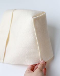 a hand is holding the edge of a piece of white material that has been folded in half