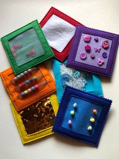 four different colored frames with buttons and beads in them on a white surface, one is made out of fabric