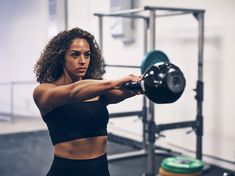 a woman is holding a barbell in the gym