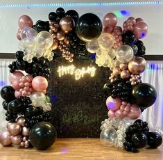 an arch made out of balloons with the words happy birthday written in gold and black