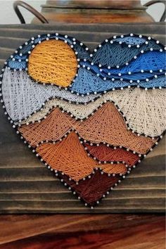 a heart made out of string and beads on top of a wooden box with an iron handle