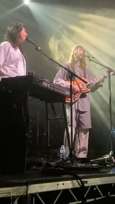 two people on stage playing instruments and singing